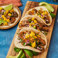 tacos with flour tortillas and mango salsa on cutting board